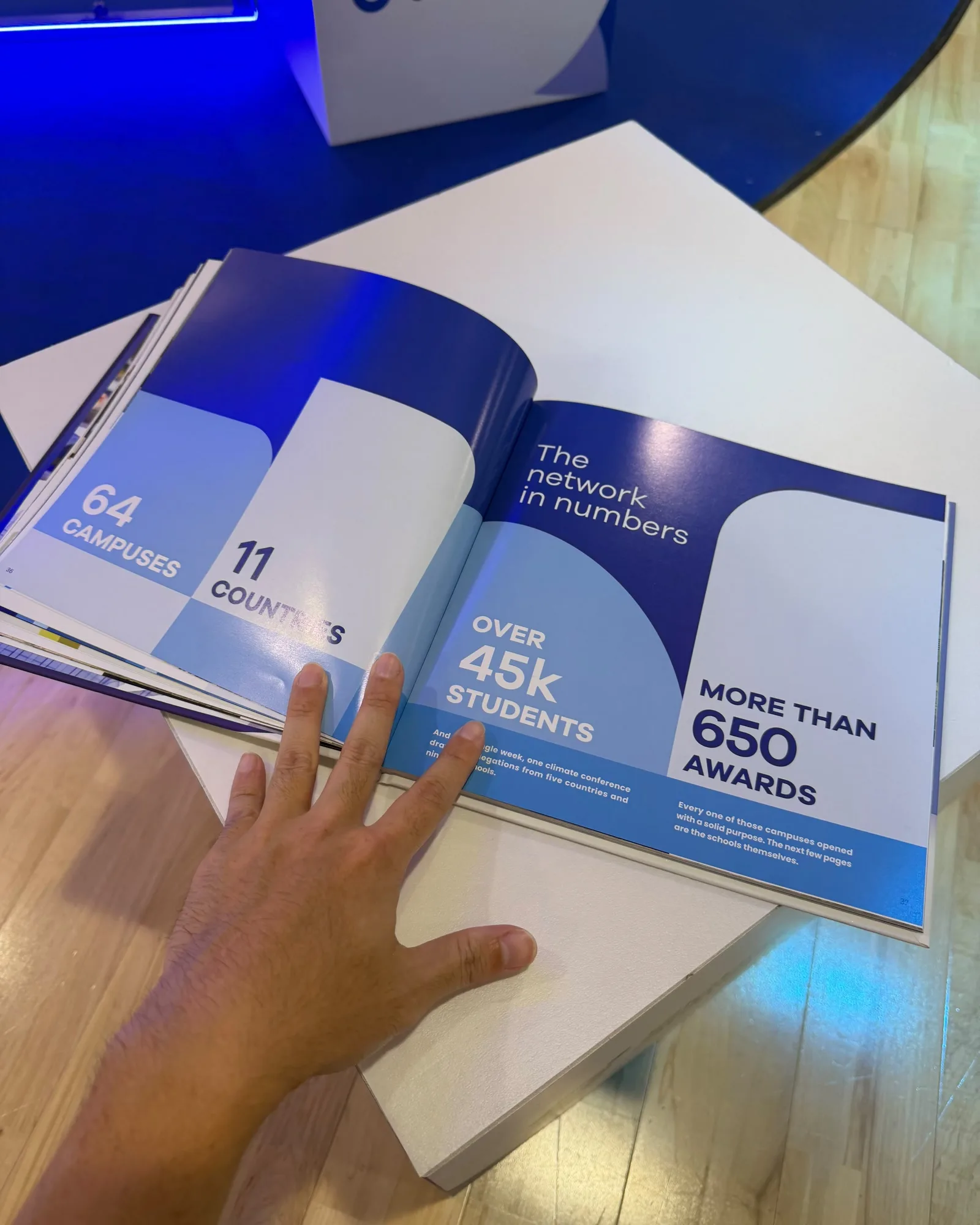 The printed GSG25 book open on the launch plinth at its network-in-numbers spread: 64 campuses, 11 countries, over 45,000 students and more than 650 awards.
